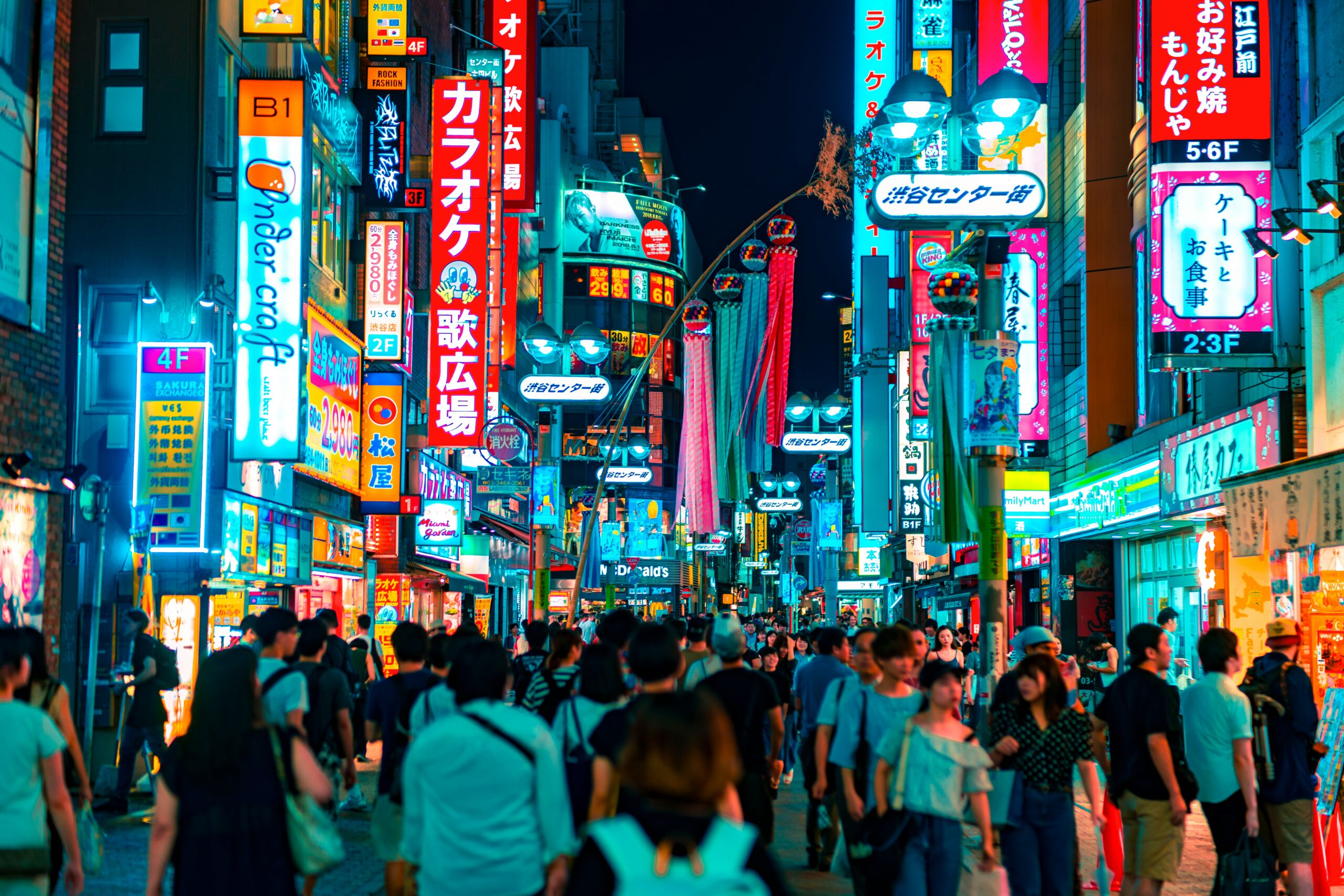 Neon-lit shopping street in Tokyo filled with signage and foot traffic, highlighting the importance of local branding and visibility in Japanese digital marketing